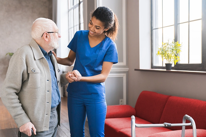 A community care nurse attentively assists a senior in their home, embodying compassionate and professional adult care services. This interaction supports the senior's ability to maintain an independent lifestyle in their own environment.