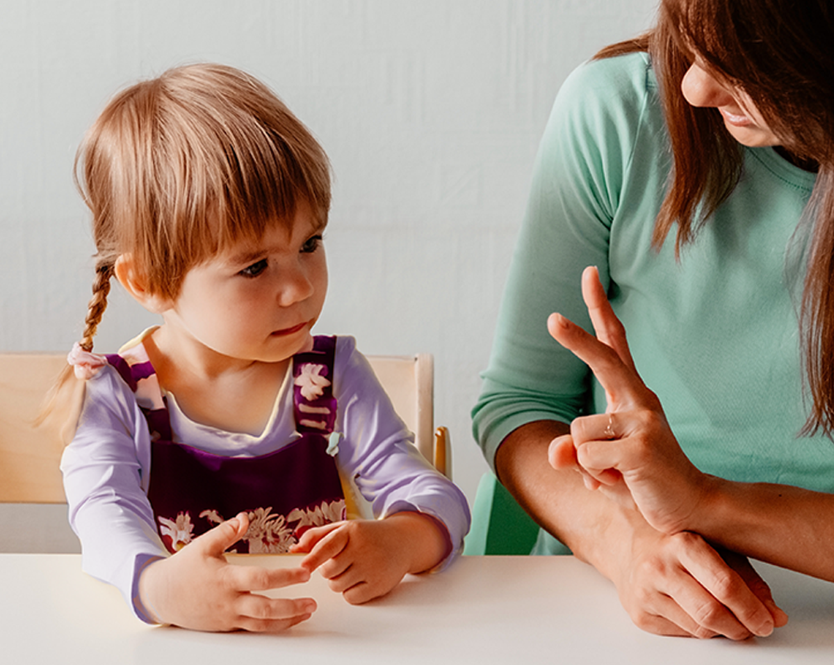 An experienced therapist provides occupational therapy to a child at home, helping them to thrive in a safe and familiar environment. The therapist is engaging with the child using gestures, toys and activities, tailored to enhance the child's daily living skills.