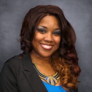 Headshot of Crystal Henry, a team member, smiling warmly at the camera. She has shoulder-length curly hair and is wearing professional attire.